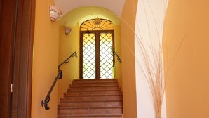 A staircase with a tiled floor leading to a door with a glass panel.
