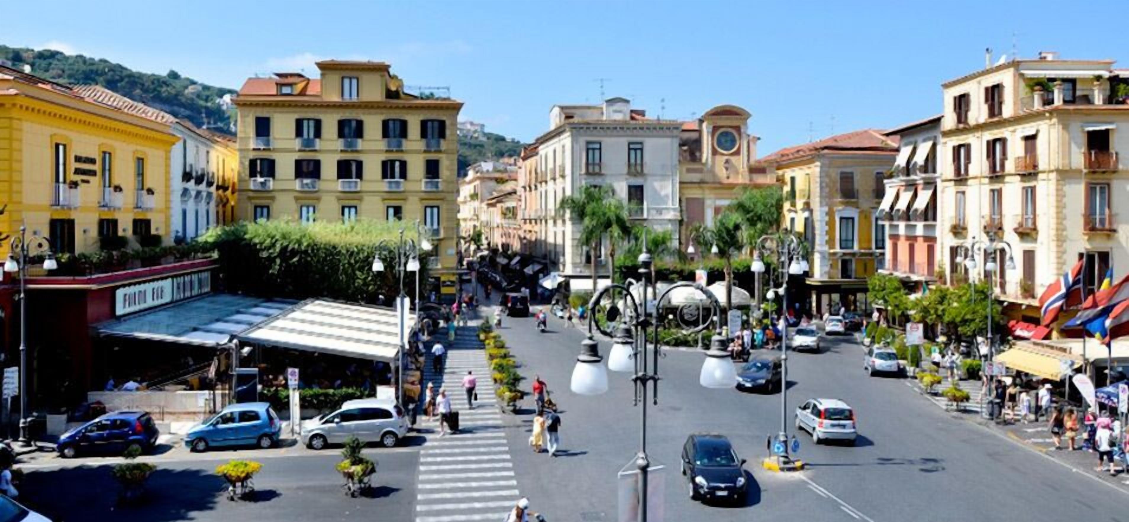 Vista de la calle con edificios, un paso de peatones y automóviles.