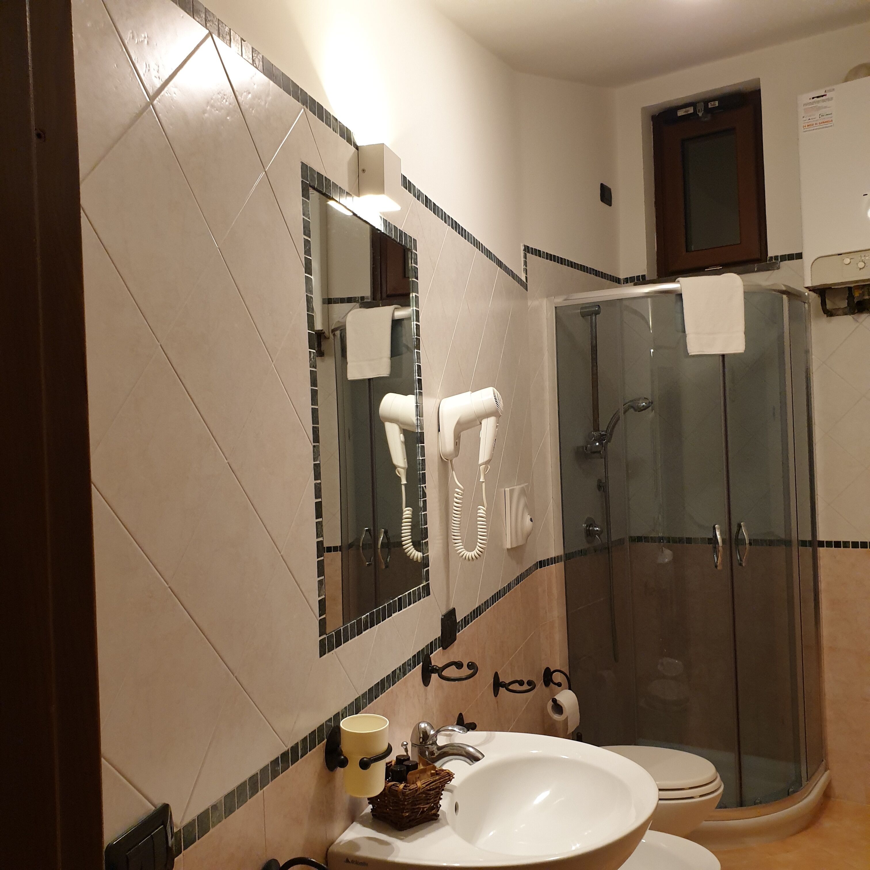 A bathroom with a large mirror, a sink, a toilet, and a glass-enclosed shower.