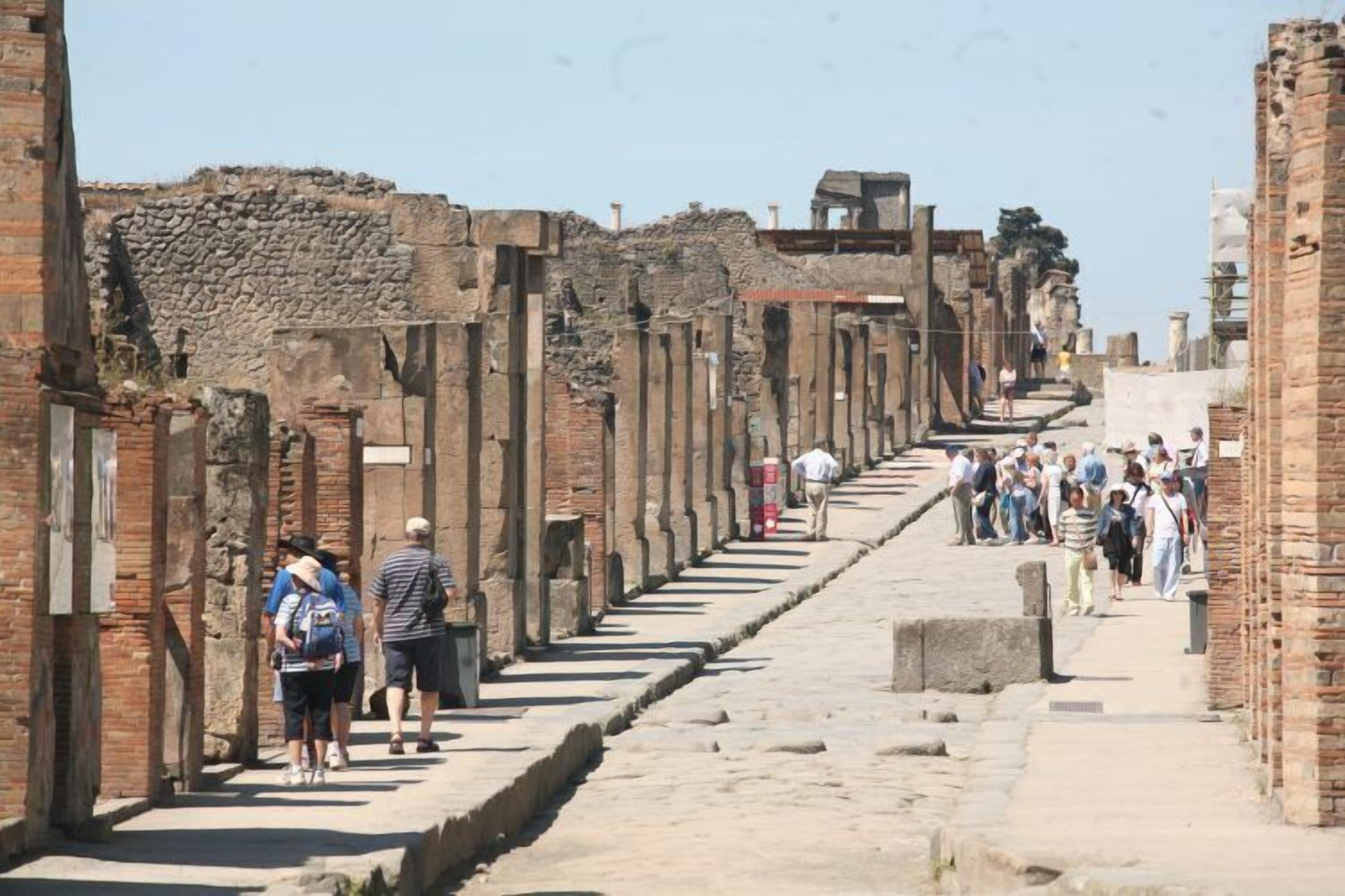 Une ancienne rue romaine, avec des ruines et des visiteurs.