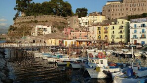 A coastal town with colorful buildings, a dock with boats, and a hillside.