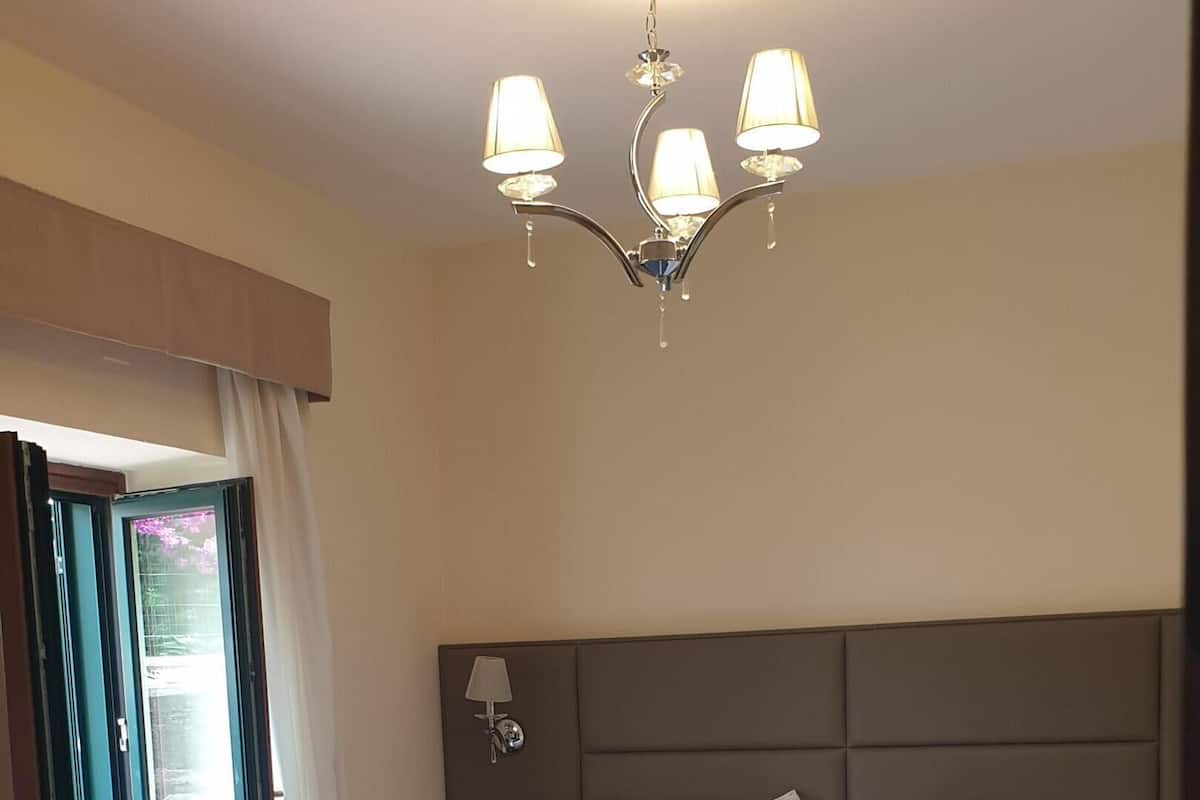 A hotel room with a bed, a nightstand, a lamp, and a window with curtains.