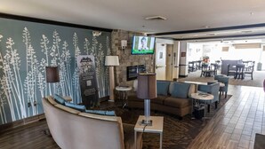 A modern hotel lobby with a curved seating area, a flat-screen TV, a fireplace, and a stone accent wall. - Sleep Inn & Suites Evansville - Casper (Evansville)