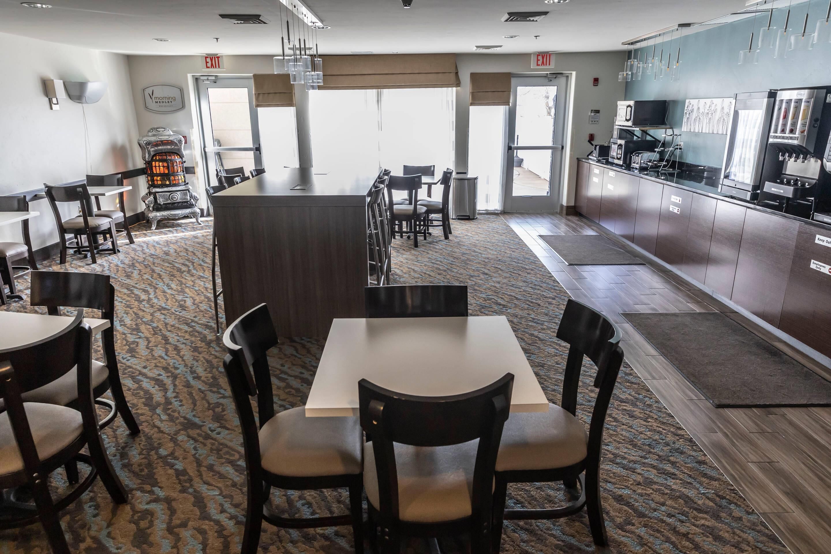 Um saguão de hotel com área de bar central, vários arranjos de assentos e uma cozinha.