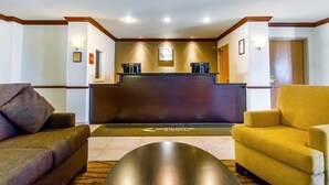 A reception area with a dark reception desk, two sofas, and a coffee machine. - Sleep Inn & Suites Evansville - Casper (Evansville)