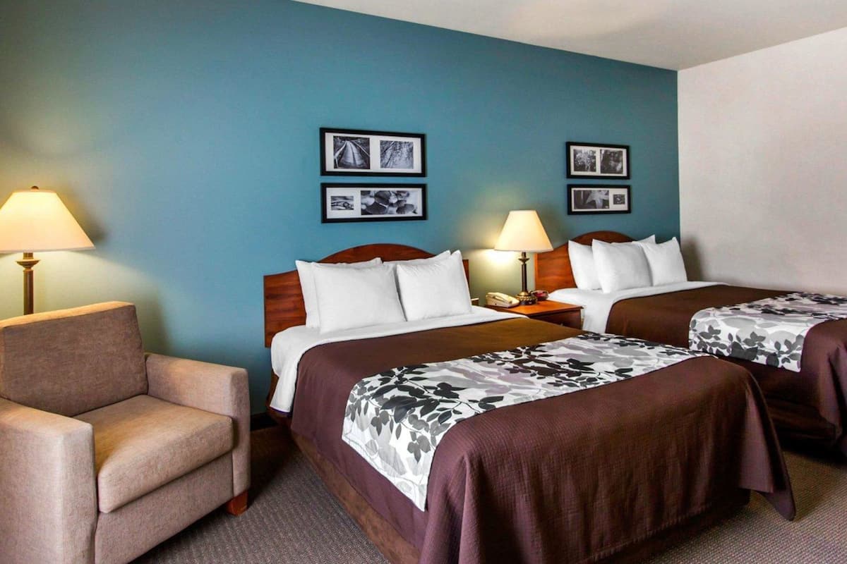 A hotel room with two beds, a sofa, and a nightstand with lamps.