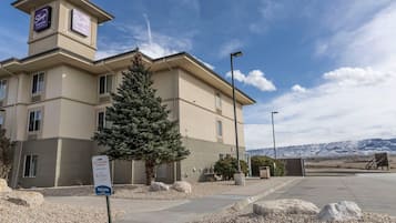 A hotel with a sign indicating 'Gold Platinum & Choice' accommodations, a welcoming sign, and a view of mountains in the background.