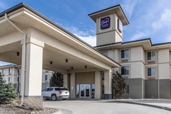 A hotel with a covered entrance, a sign for 'Sleepz Inn & Suites,' and a parked SUV.