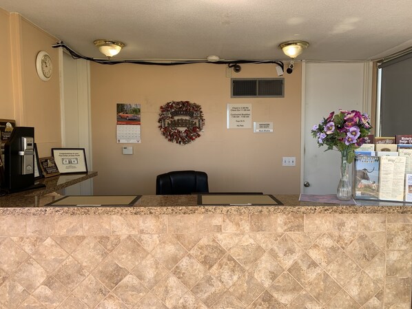 A reception area with a marble counter, a clock, a wreath, a calendar, and a vase with flowers.