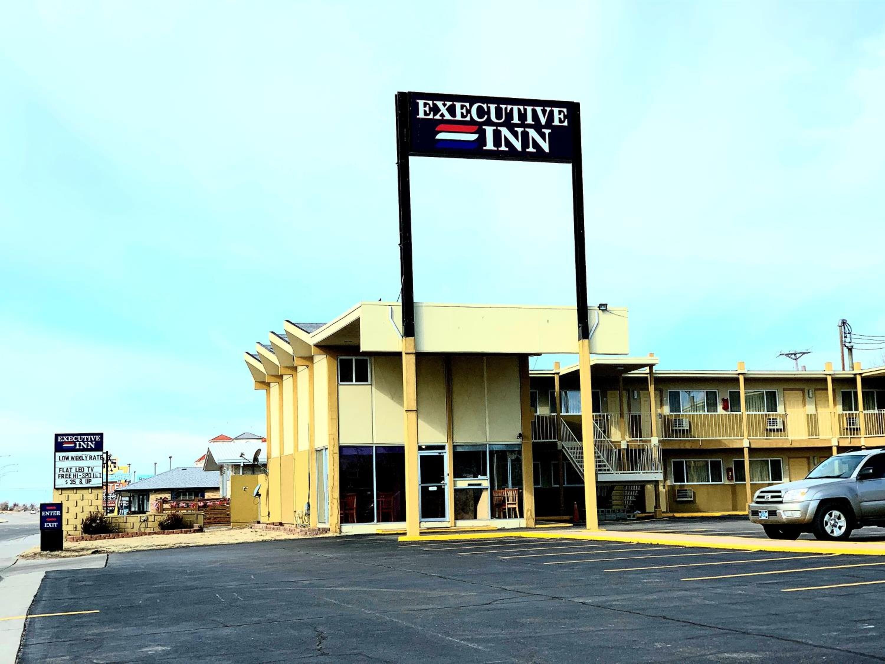 An Executive Inn with a prominent sign, a flat roof, and a parking lot.