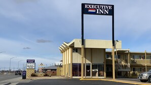 An Executive Inn motel with a prominent sign, a flat roof, and a parking lot. - Executive Inn (Dodge City)