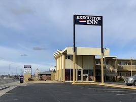 Motel Executive Inn con un letrero llamativo, techo plano y estacionamiento.