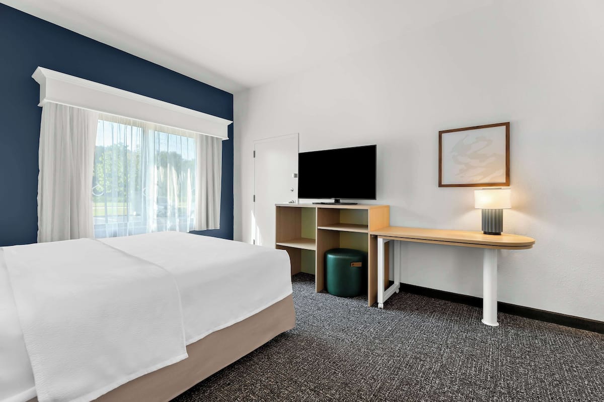 A hotel room with a bed, a desk, a television, and a lamp.