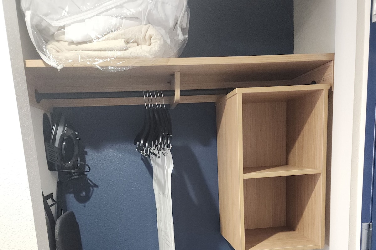 A small room with a blue wall, a wooden shelf, and a coat rack.