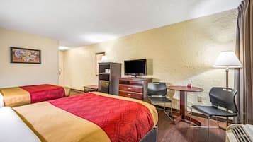 Habitación de hotel con dos camas, un escritorio con televisor, una silla y una mesa.