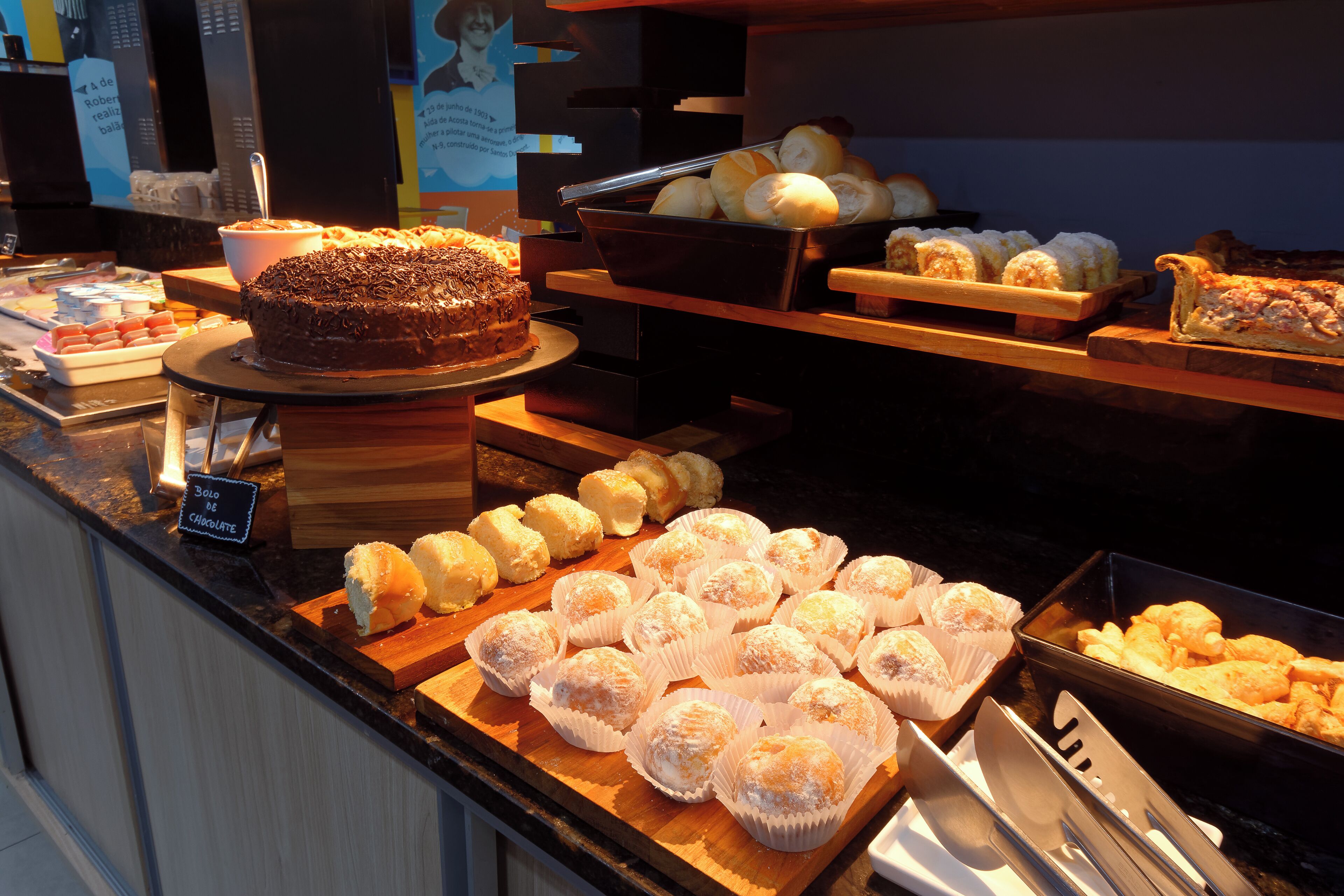 Un buffet proposant une variété de produits de boulangerie, notamment des pâtisseries, du pain et un gâteau au chocolat.