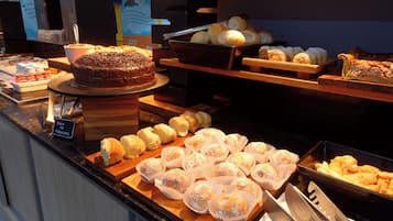 Un buffet proposant une variété de produits de boulangerie, notamment des pâtisseries, du pain et un gâteau au chocolat.