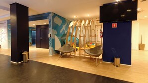 A modern lobby with a blue wall, a large TV, and a seating area with chairs. - Golden Tower Express Anhembi by Fênix Hotéis (São Paulo)