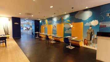 Un restaurant au décor moderne, avec des tables et des chaises disposées dans un espace vaste et bien aménagé.