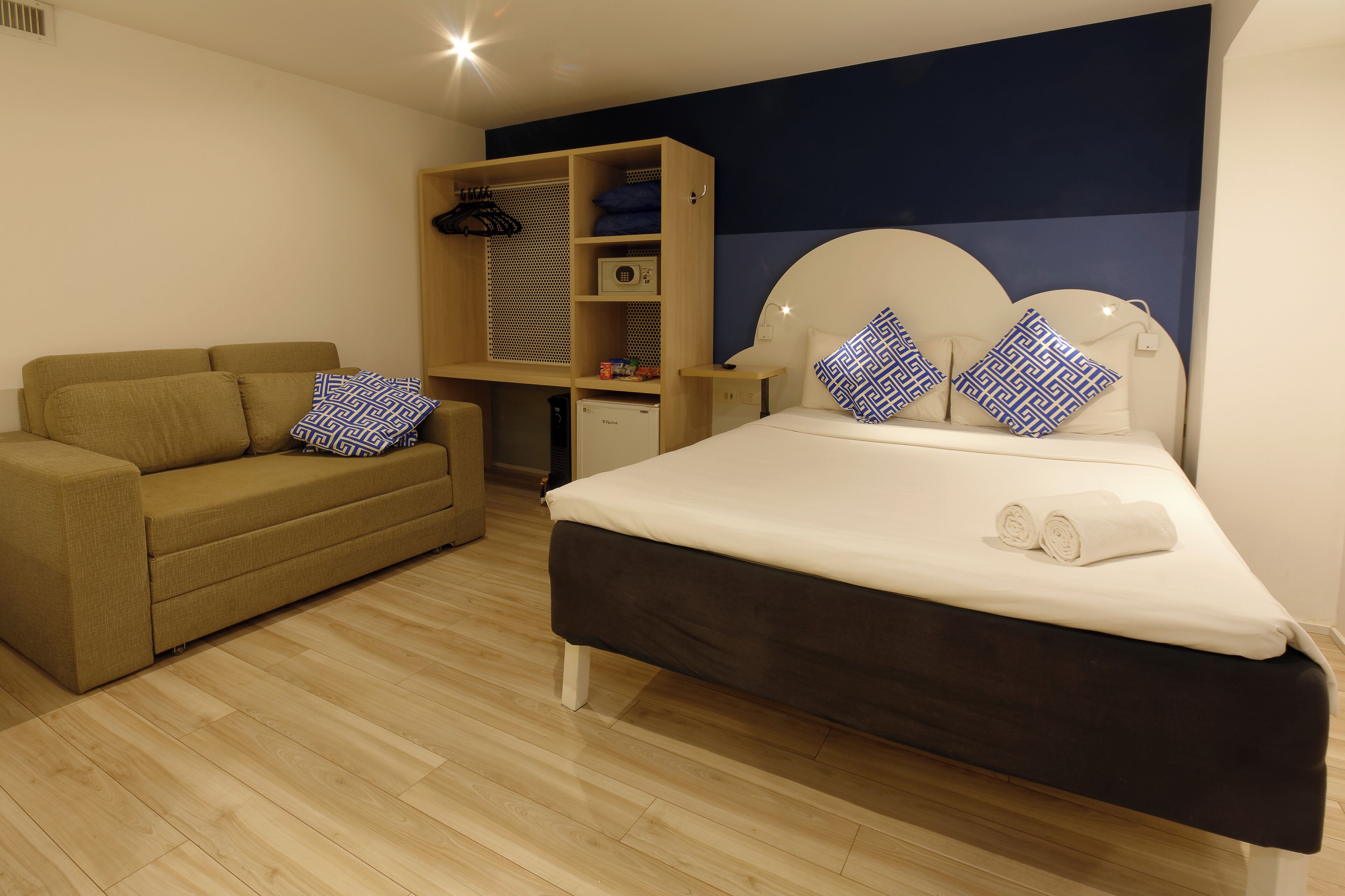 A modern bedroom with a bed, a sofa, a wardrobe, and a desk.