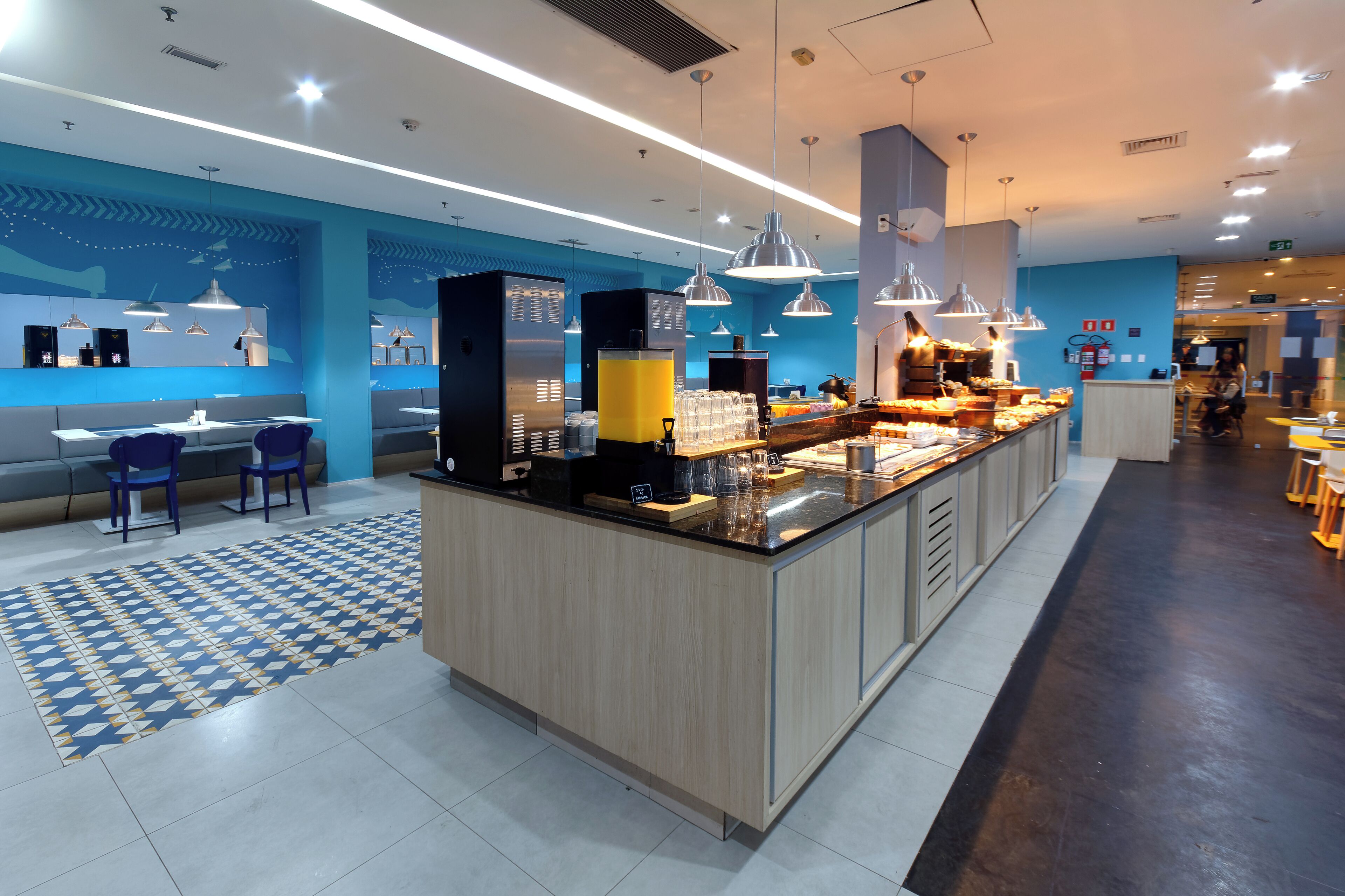 A modern hotel lobby with a central island counter, seating area, and a patterned rug.