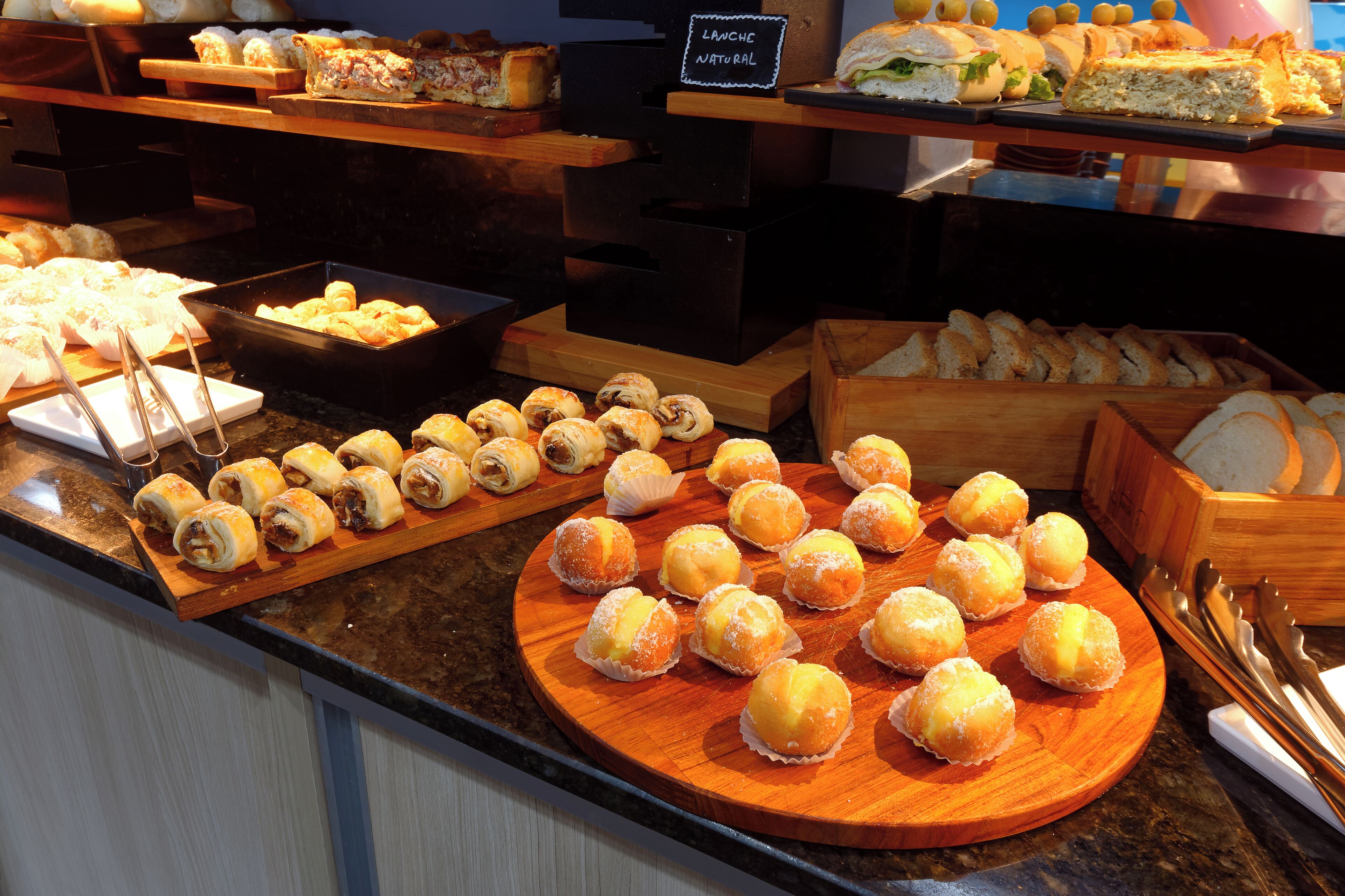 A variety of baked goods displayed on a counter, including pastries and sandwiches.