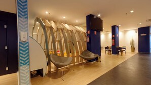 A modern interior with wooden slat partitions, two grey chairs, a table, and a potted plant. - Golden Tower Express Anhembi by Fênix Hotéis (São Paulo)