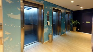 An elevator area with three elevators, a trash can, and a potted plant. - Golden Tower Express Anhembi by Fênix Hotéis (São Paulo)