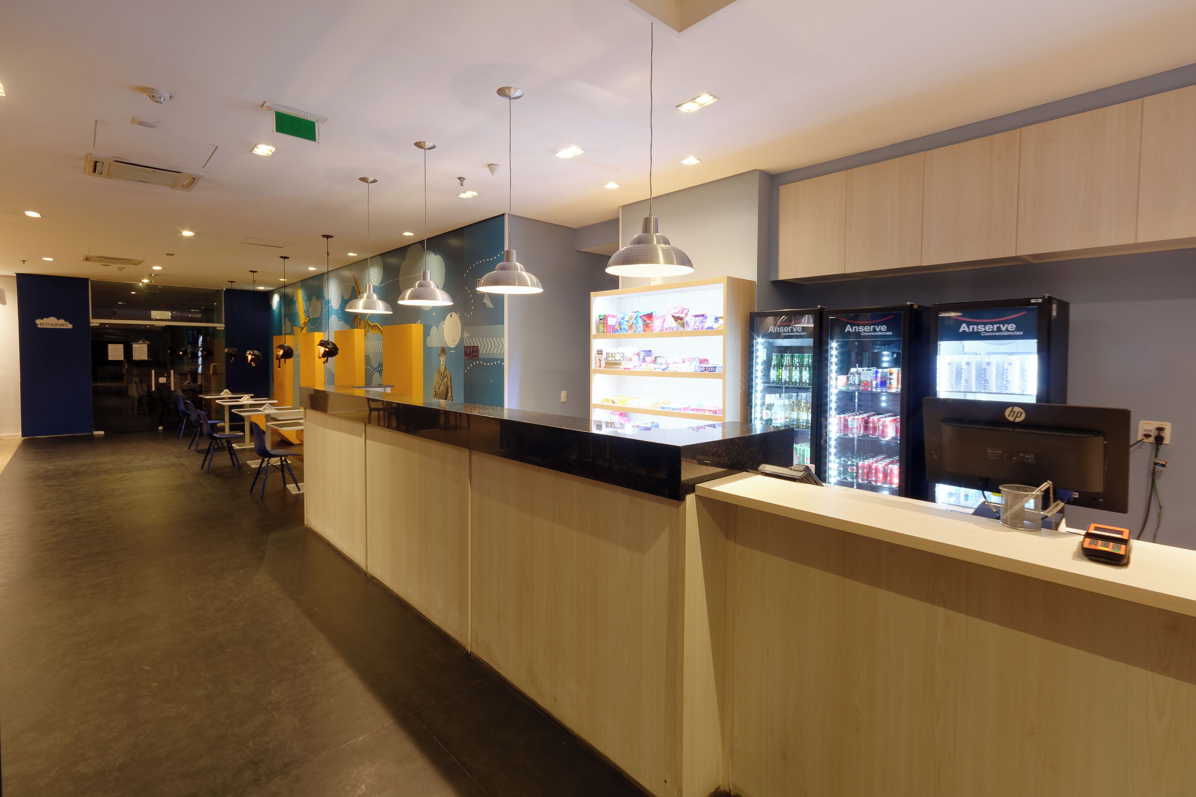 A modern hotel reception area with a counter, vending machines, and seating.