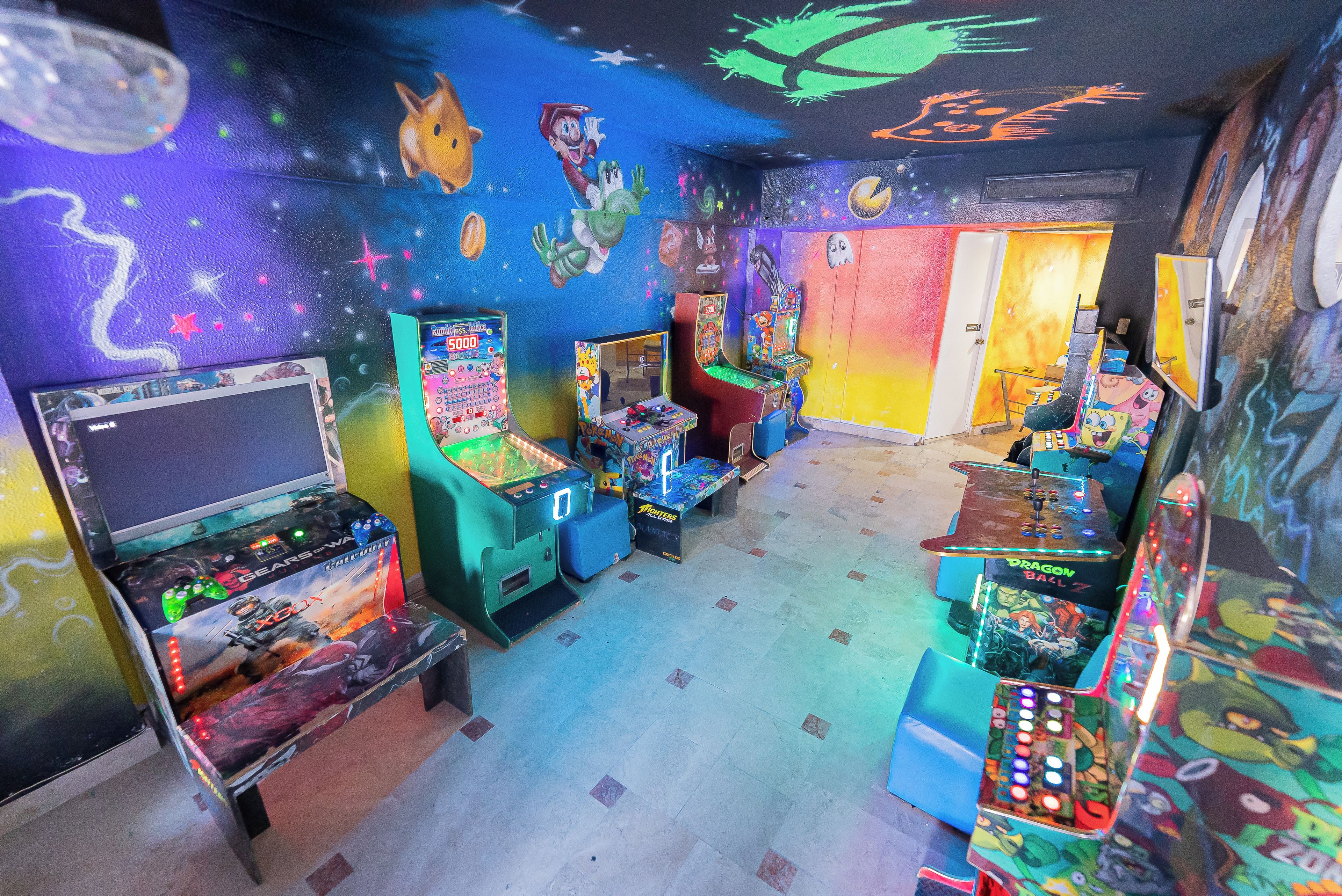 A room with arcade games, colorful murals, and a Star Wars-themed ceiling.