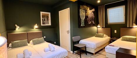 A hotel room with two beds, a desk, a chair, and a window with curtains.