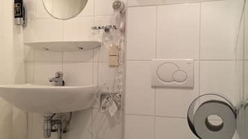 Een badkamer met een wastafel, spiegel, haardroger en toilet.