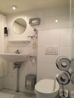 Un baño con lavamanos, espejo, secador de pelo y retrete.