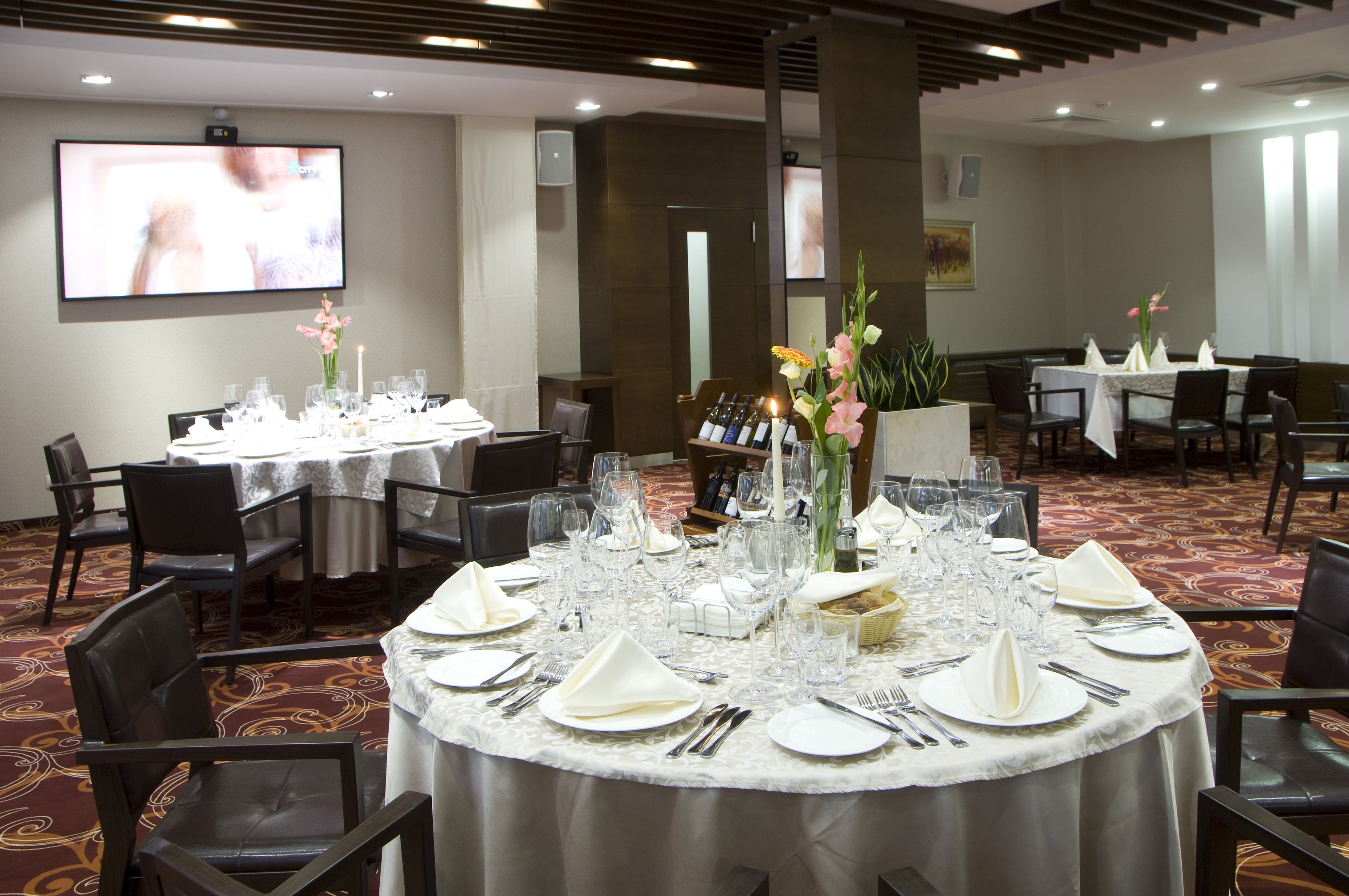 A banquet hall with round tables set for dining, equipped with glassware and napkins.