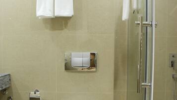 Un baño moderno con inodoro, cabina de ducha con vidrio y un perchero con dos toallas.
