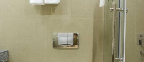 Un baño moderno con inodoro, cabina de ducha con vidrio y un perchero con dos toallas.
