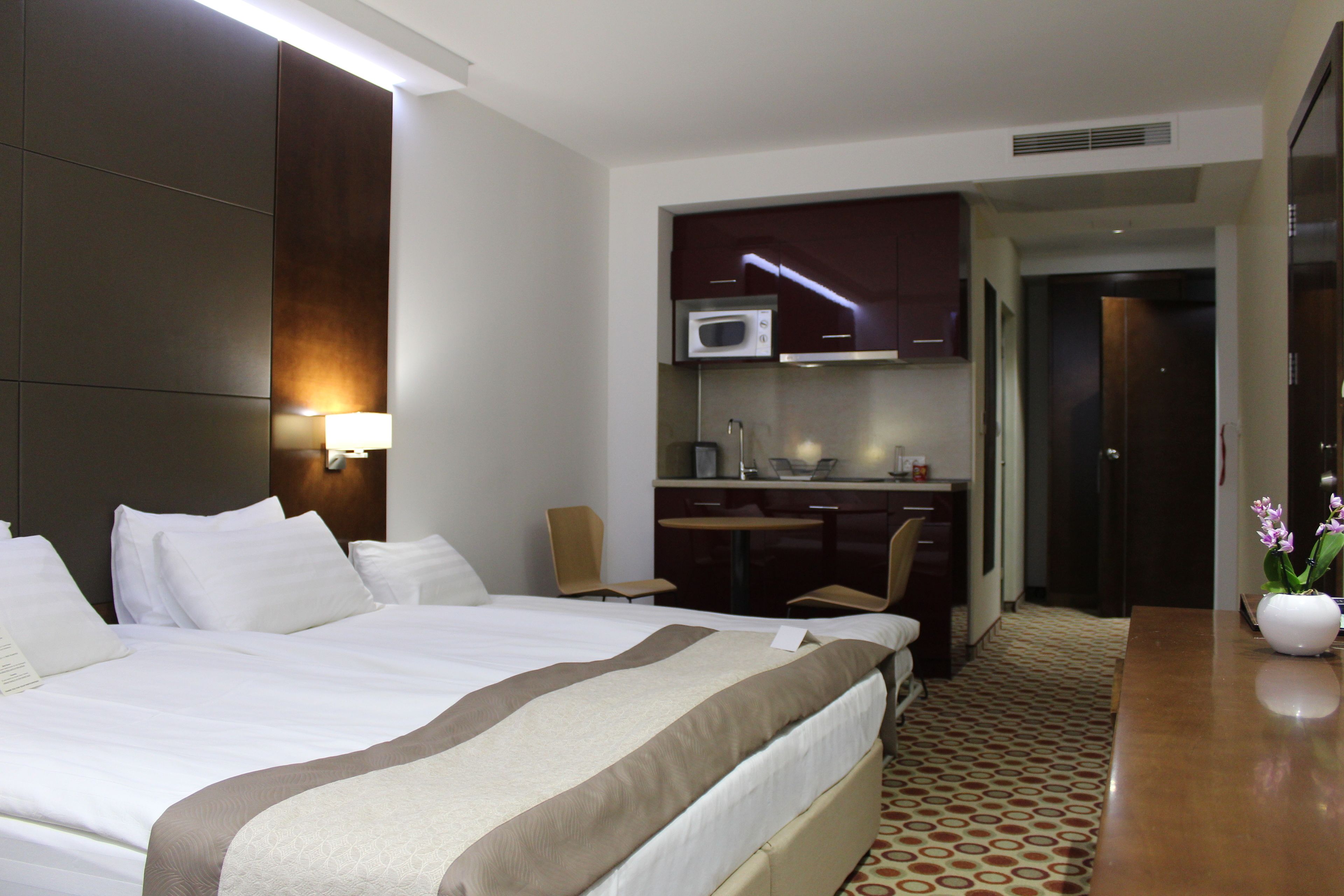 Une chambre d’hôtel avec un grand lit, un bureau avec un ordinateur, un four à micro-ondes et un petit coin salon.