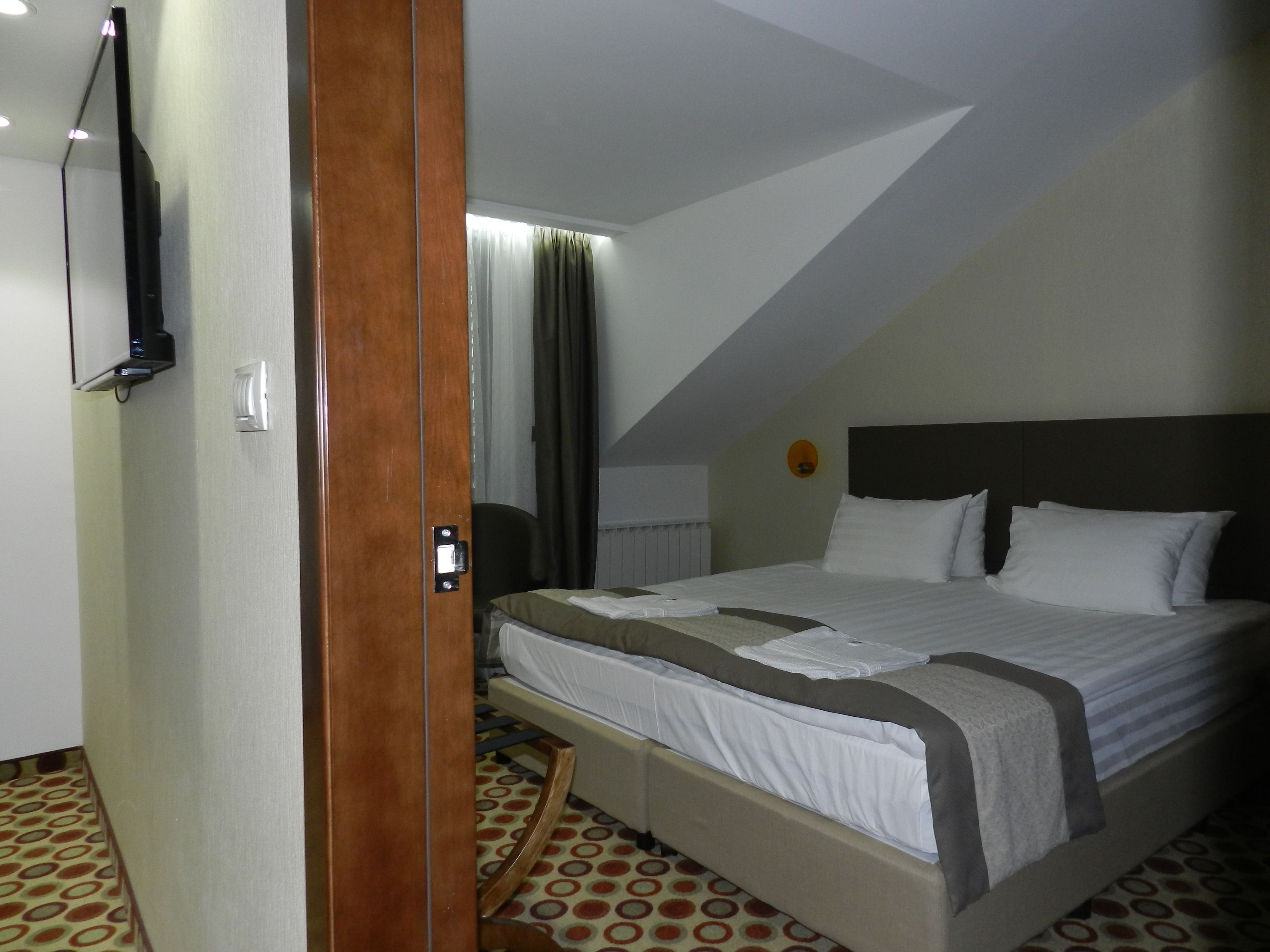 A hotel room with a bed, a desk, a chair, and a window with curtains.