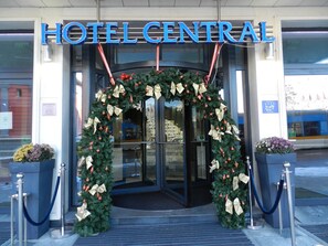 La entrada del Hotel Central adornada con un adorno navide ño y un lazo decorativo.
