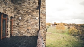 Un edificio de piedra con balcón y vista a un espacio verde con árboles.