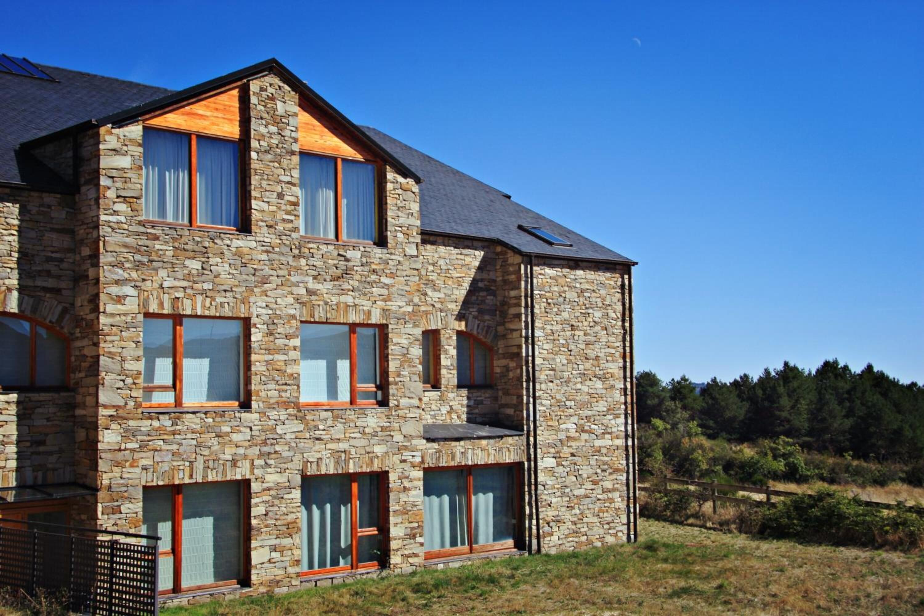 Un moderno edificio de piedra con múltiples ventanas y techo inclinado.