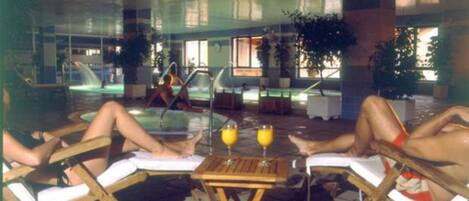 Zona junto a la piscina con sillones de descanso, una mesa y una piscina.
