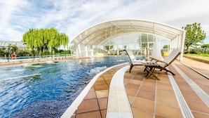Une piscine équipée de deux chaises longues et entourée d’une structure en verre.