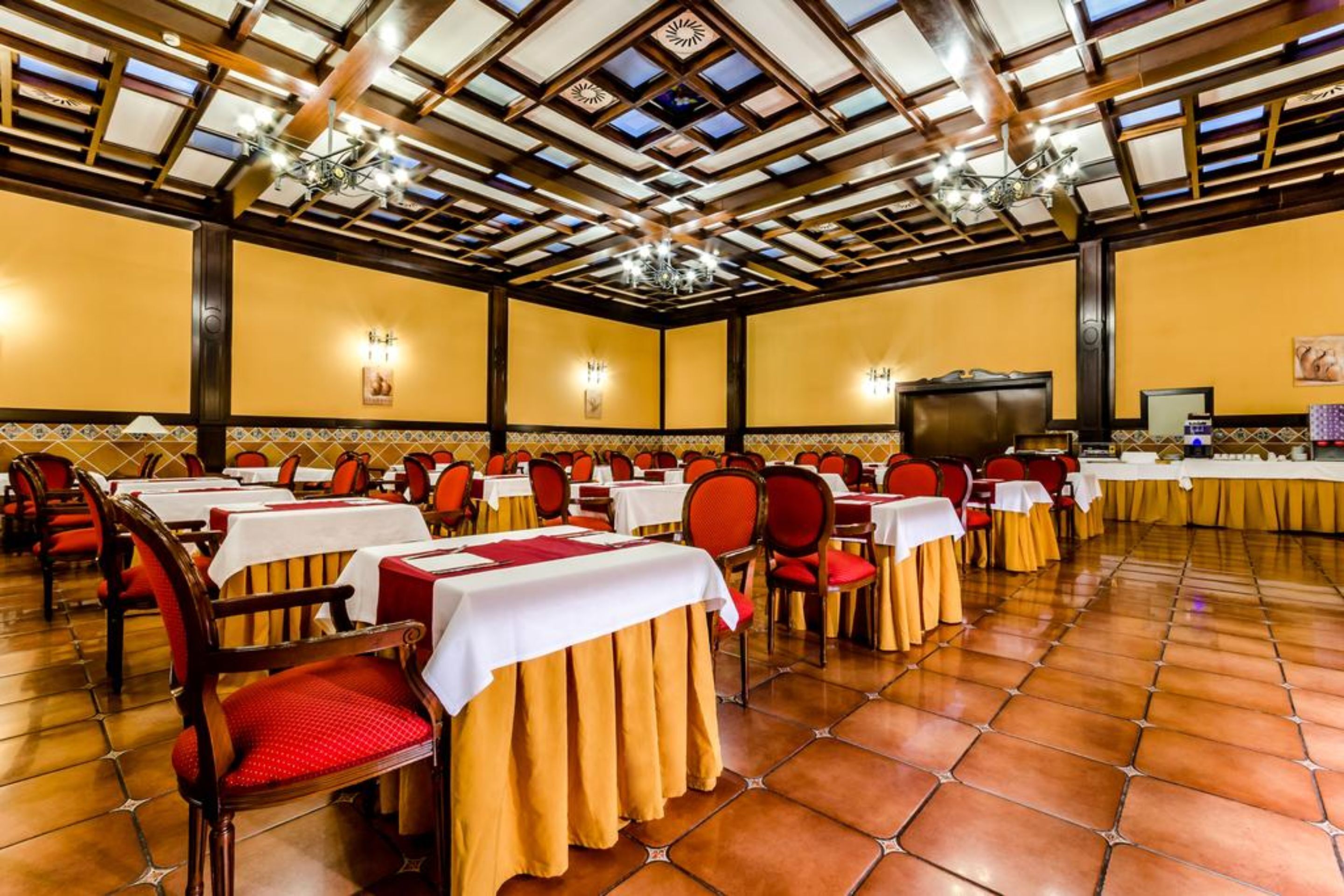 A banquet hall with tables set for dining, a large screen, and a chandelier.