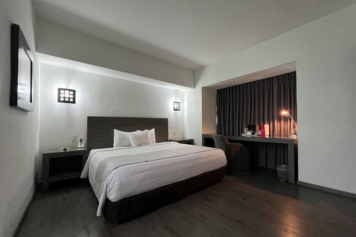 Een moderne hotelkamer met een groot bed, nachtkastjes, een bureau en een stoel.