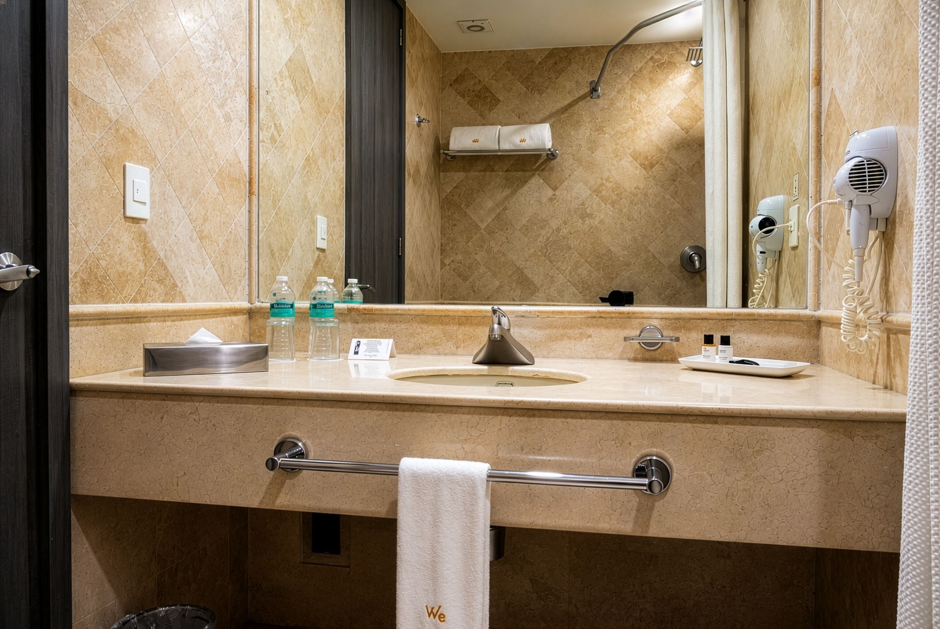 Baño con lavamanos, espejo, perchero para toallas y secador de pelo.