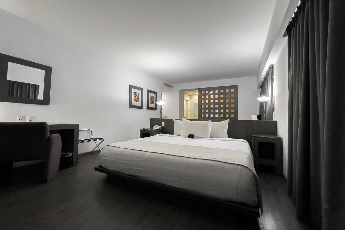 Een moderne hotelkamer met een groot bed, nachtkastjes, een bureau en een stoel.