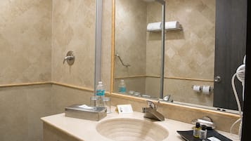 Un baño con lavamanos, espejo, toallero y artículos de aseo.