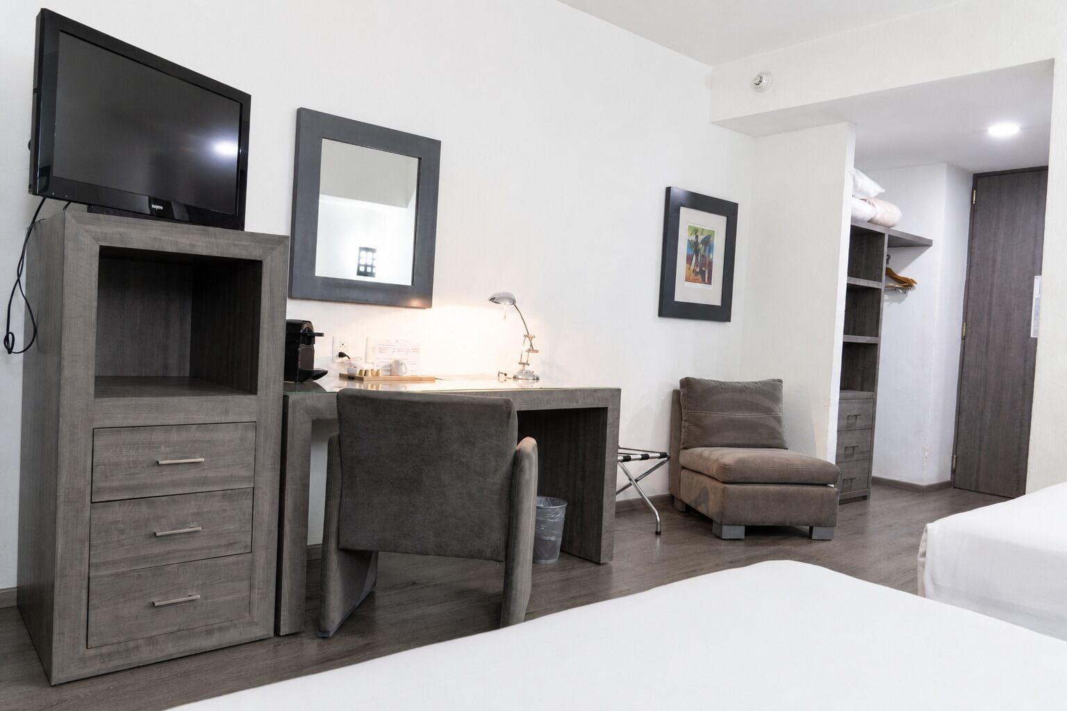 Una habitación de hotel con escritorio, silla, cama, armario y televisor.
