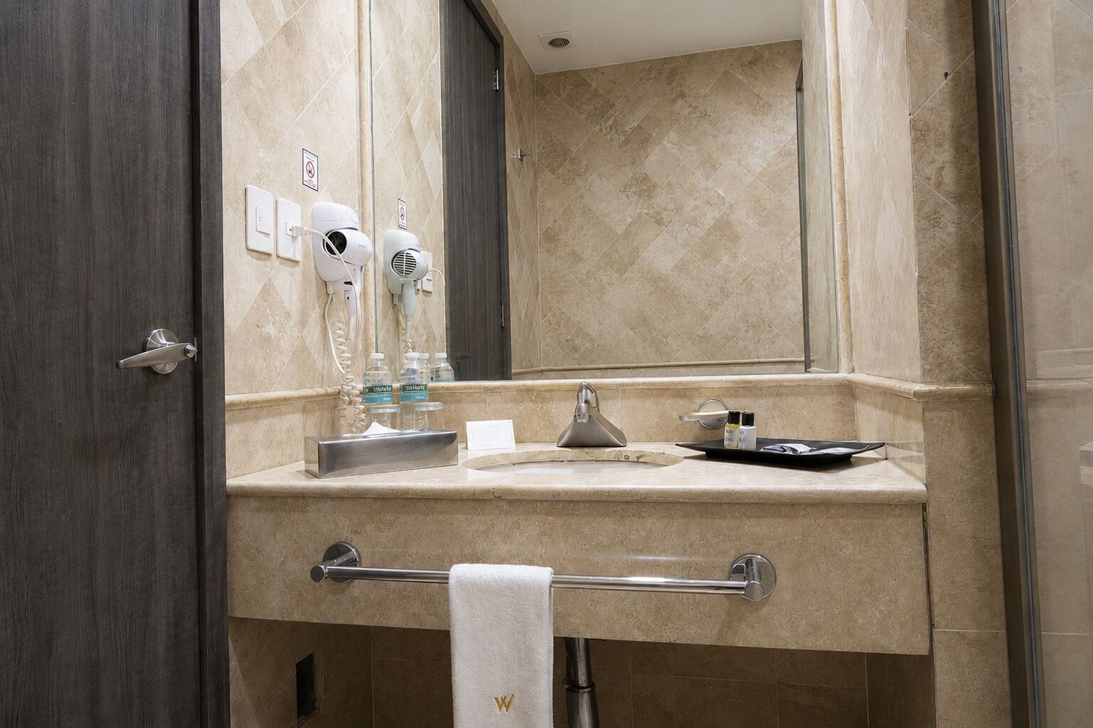 Un baño con tocador, perchero, secador de pelo y espejo.
